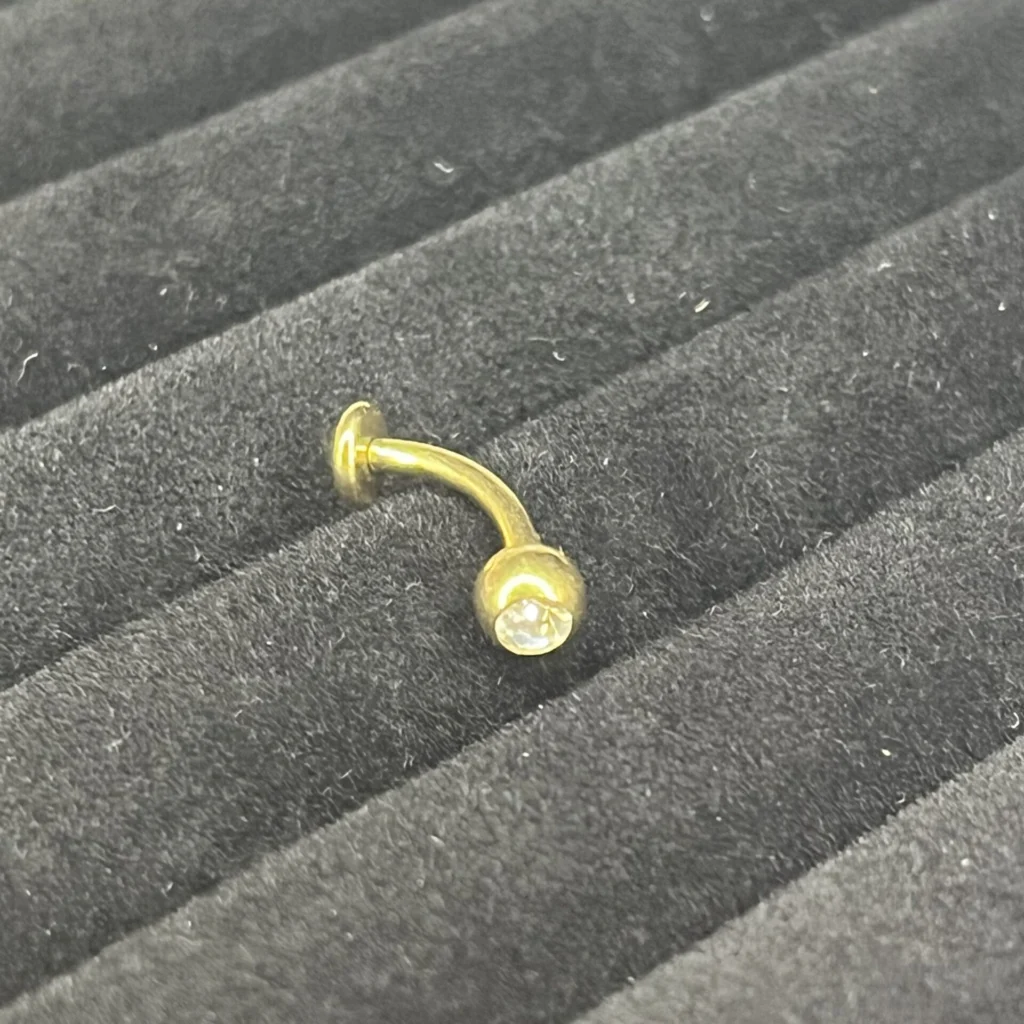 Lola - Banane nombril floating belly piercing en titane doré avec un cristal